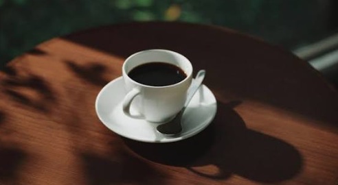 窓からの木漏れ日が差すテーブルと、一杯のコーヒー